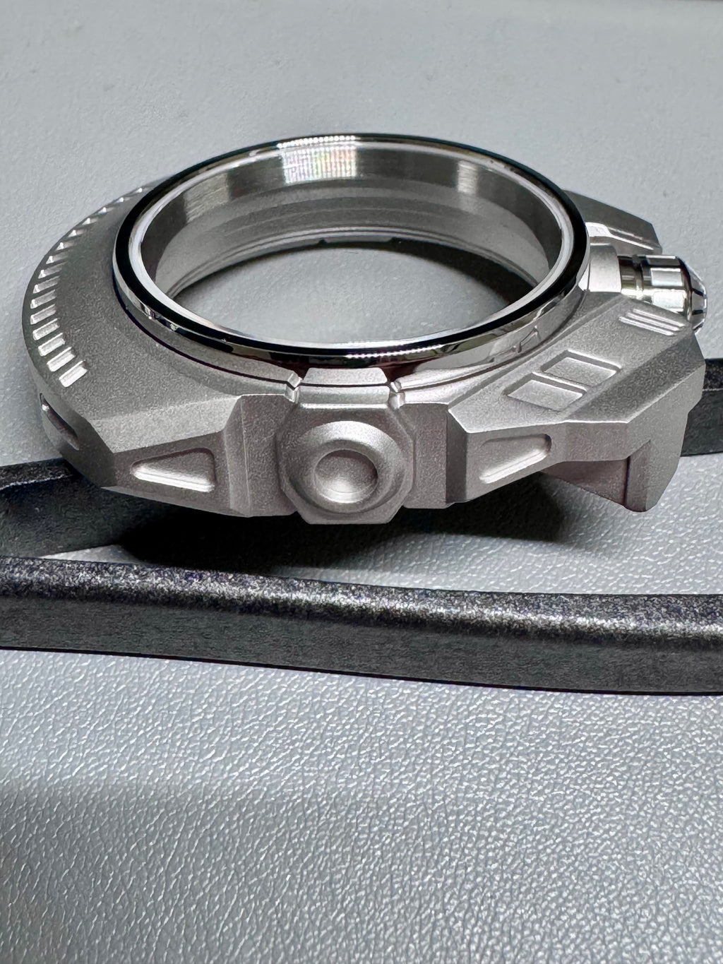 Metallic mechanical watch component on a gray surface