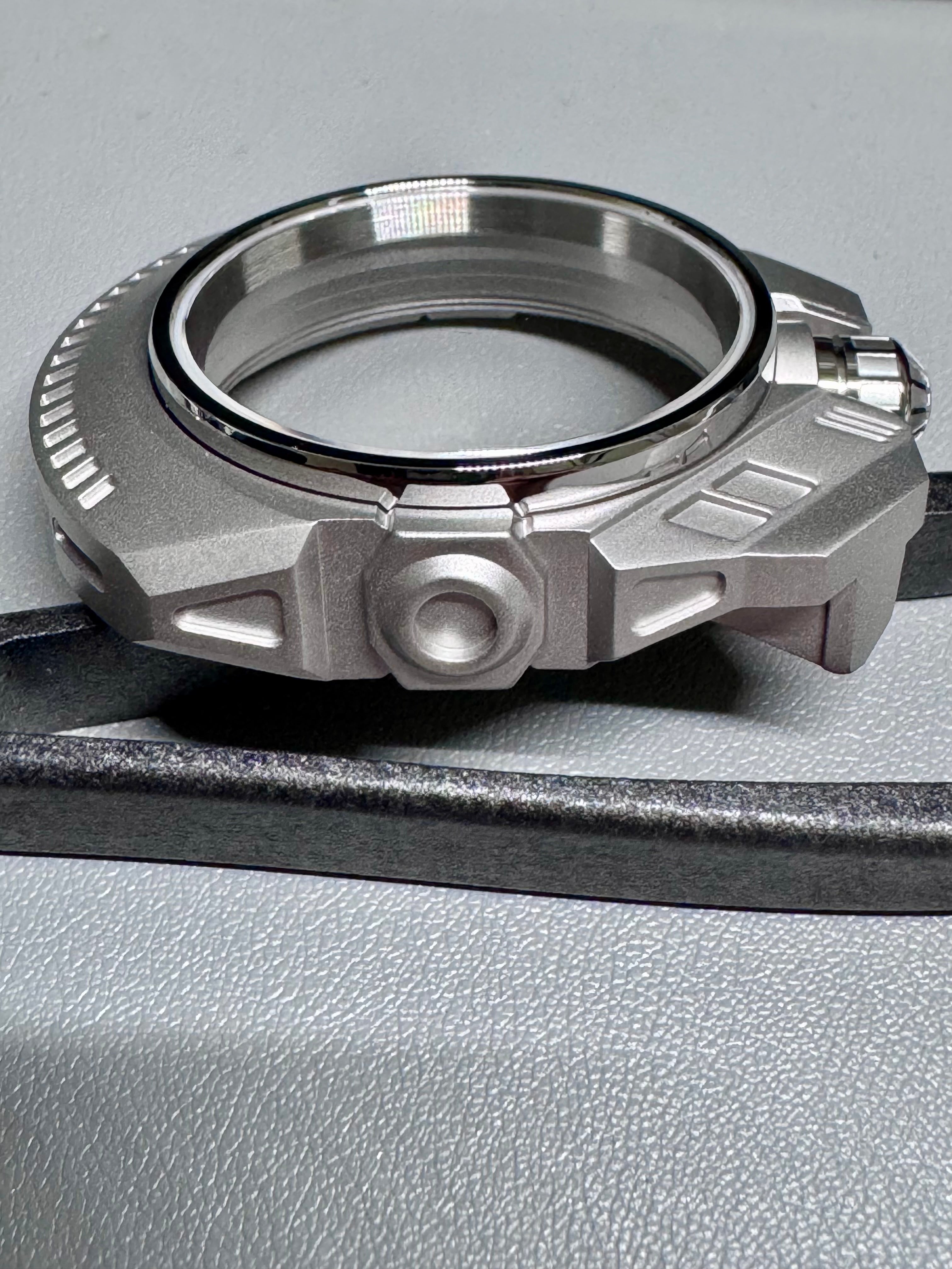 Metallic mechanical watch component on a gray surface