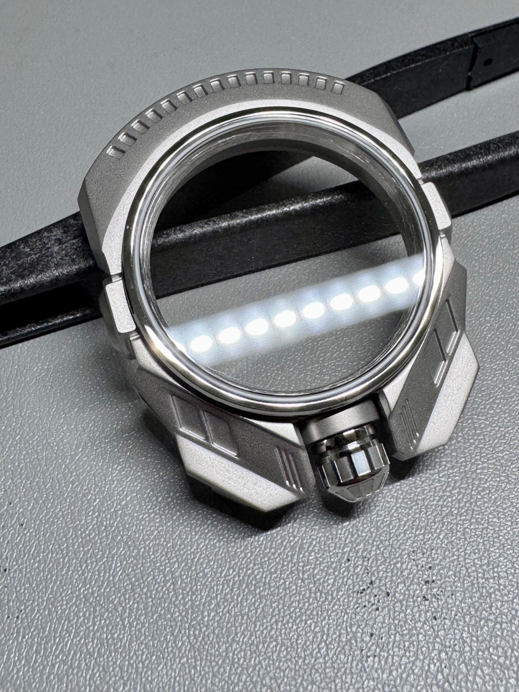Close-up of a metallic watch case on a gray surface