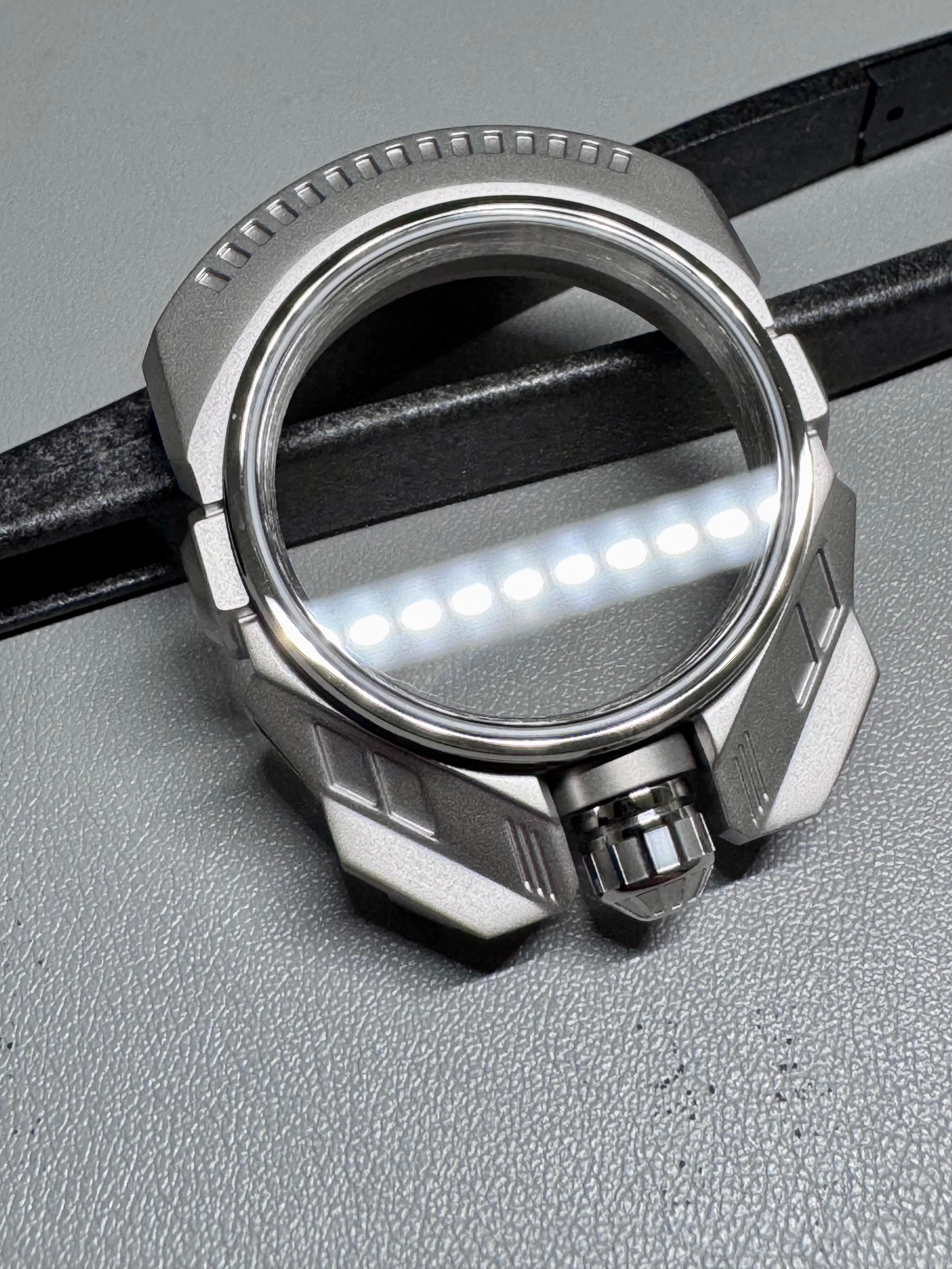 Close-up of a metallic watch case on a gray surface