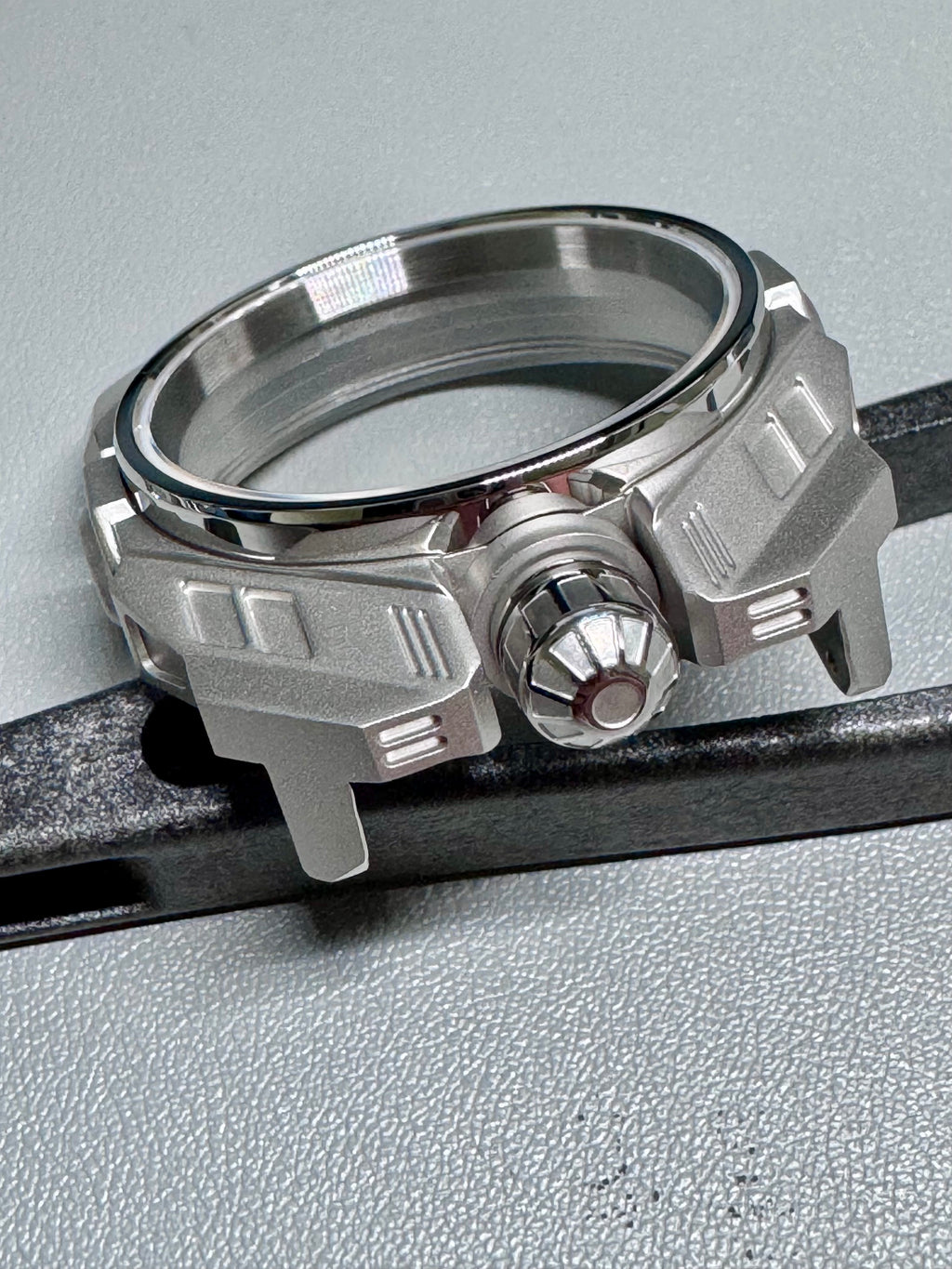 Close-up of a metallic watch part on a gray background