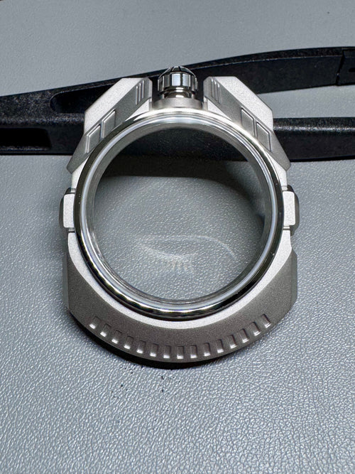 Close-up of a metallic watch case on a gray surface