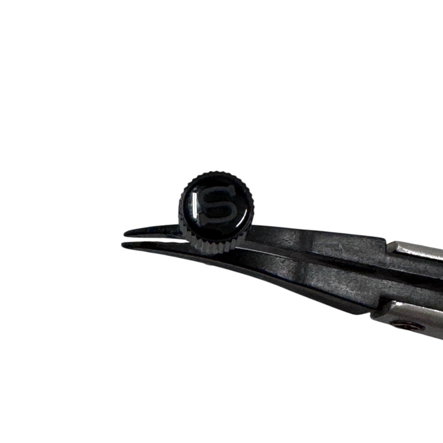 A polished black coin-edged screw-down crown for a watch, held by a pair of tweezers against a white background, top view