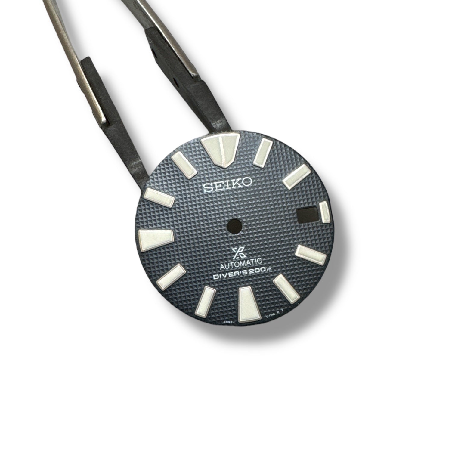 A Seiko SRPB49 navy blue dial for watches, held by two tweezers.