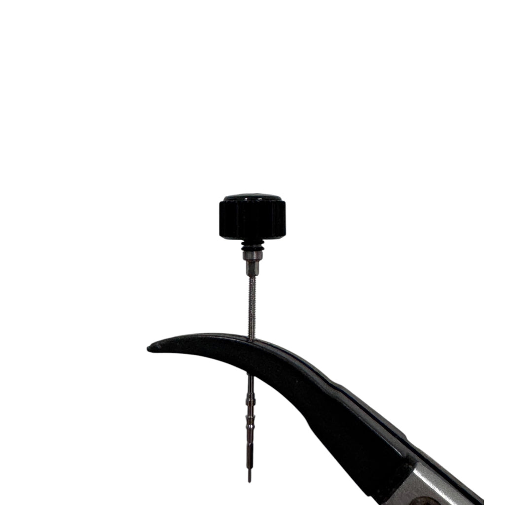 A polished black coin-edged screw-down crown for a watch, held by a pair of tweezers against a white background, side view