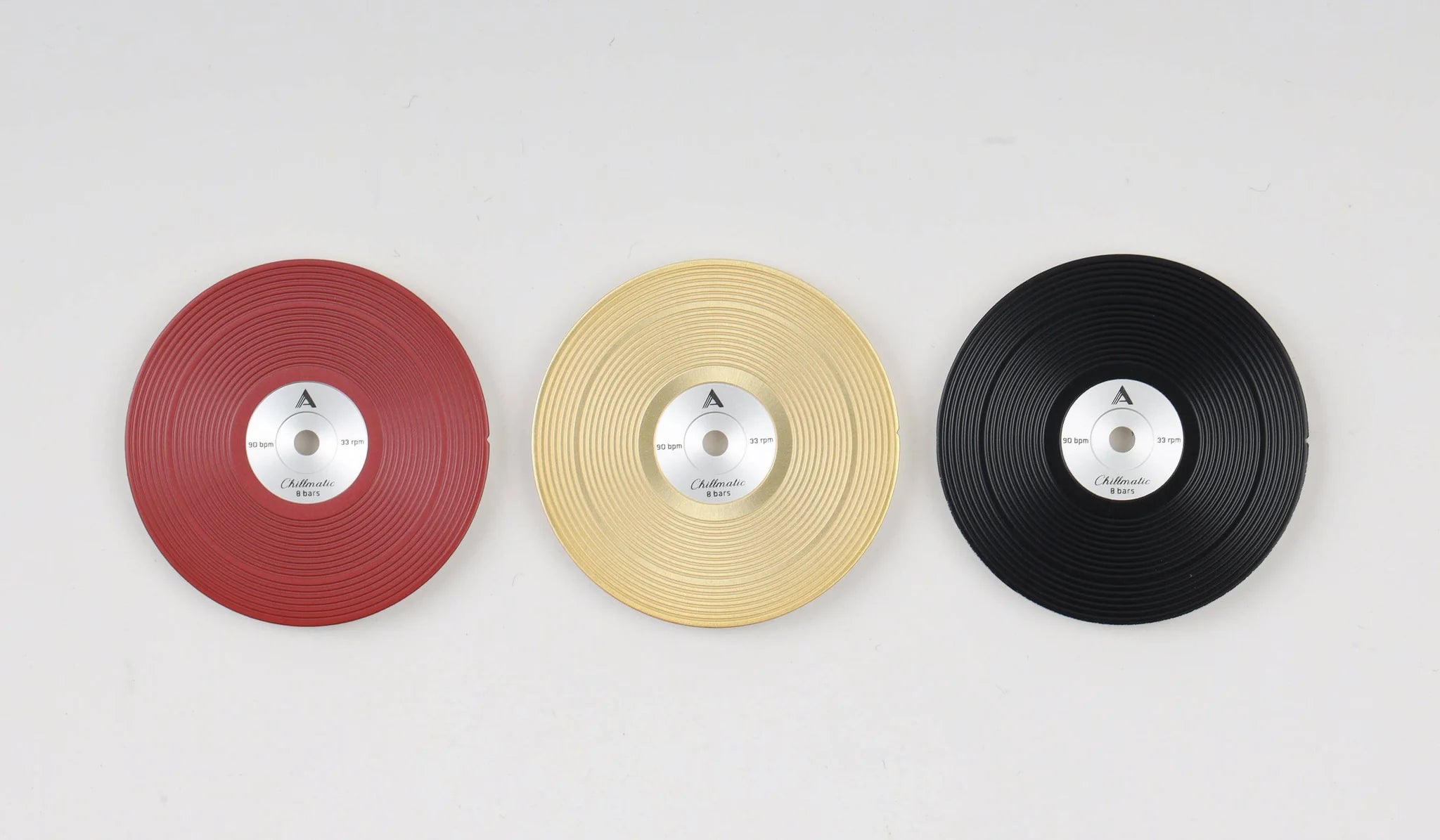 Three vinyl record-style watch dials lying flat on a surface, arranged in a row with red, yellow, and black colors.