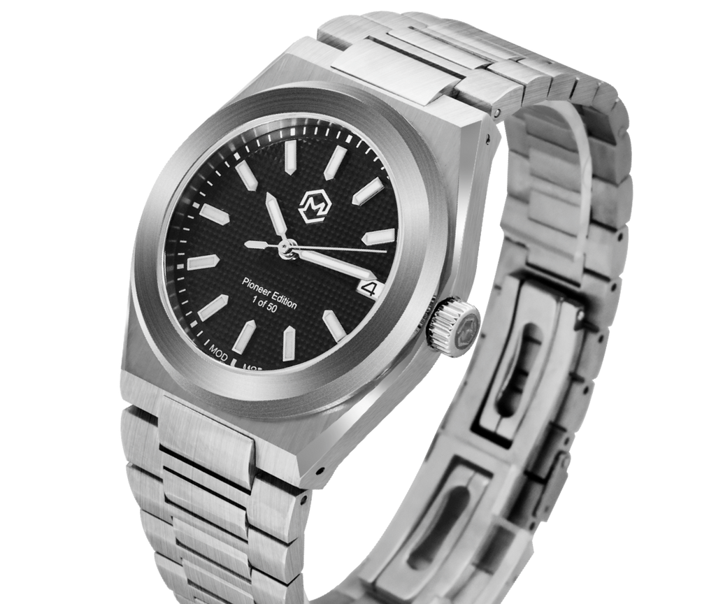A silver-toned Project MM1 Pioneer Edition watch with a black waffle dial, stainless steel bracelet, and a vulcanised rubber strap.